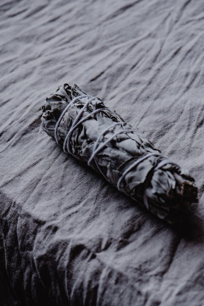 White sage smudge stick on textured cloth for spiritual cleansing and purification rituals.